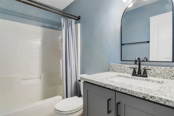 a bathroom with a granite countertop sink toilet and mirror