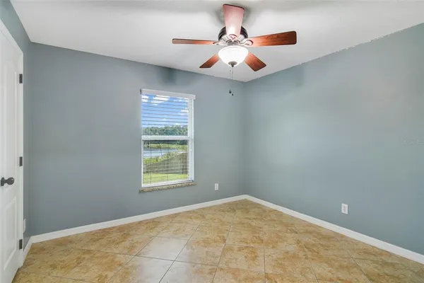 an empty room with a window and a ceiling fan