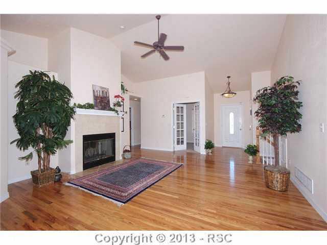15028 Herring Road Colorado Springs, CO 80908 - Photo 2 of 17 Beautiful wood flooring, cathedral ceilings, french doors to main level office and gas fireplace.