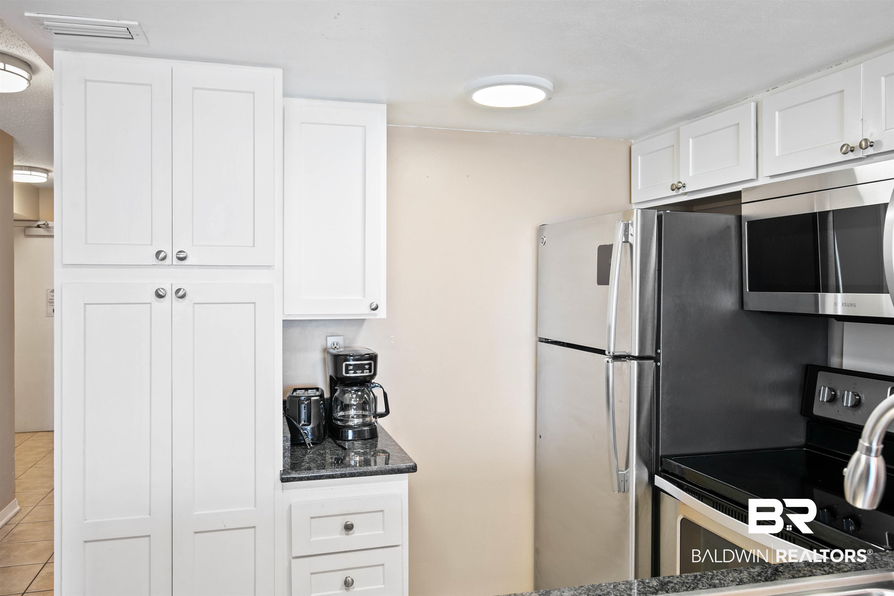 645 Plantation Road, Unit 6606 Gulf Shores, AL 36542 - Photo 16 of 60 Kitchen featuring white shaker-style cabinetry, dark granite-finish countertops, stainless steel appliances, and an integrated microwave