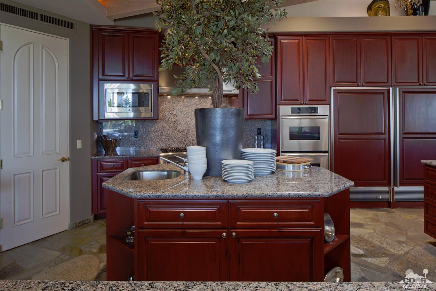 40815 Tonopah Road Rancho Mirage, CA 92270 - Photo 11 of 44 a kitchen with stainless steel appliances granite countertop a sink refrigerator and cabinets