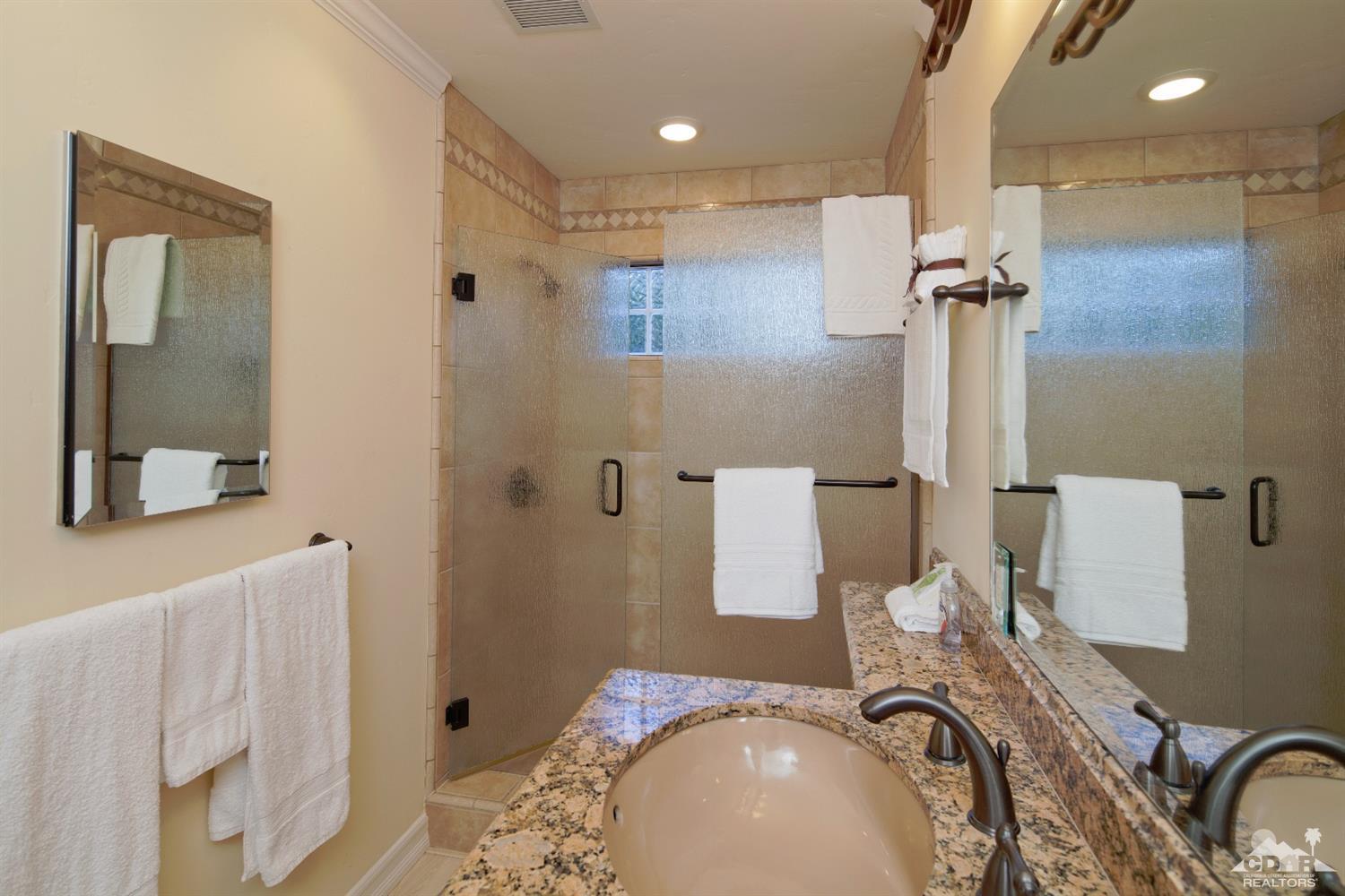 40815 Tonopah Road Rancho Mirage, CA 92270 - Photo 28 of 44 a bathroom with a granite countertop sink a mirror and shower