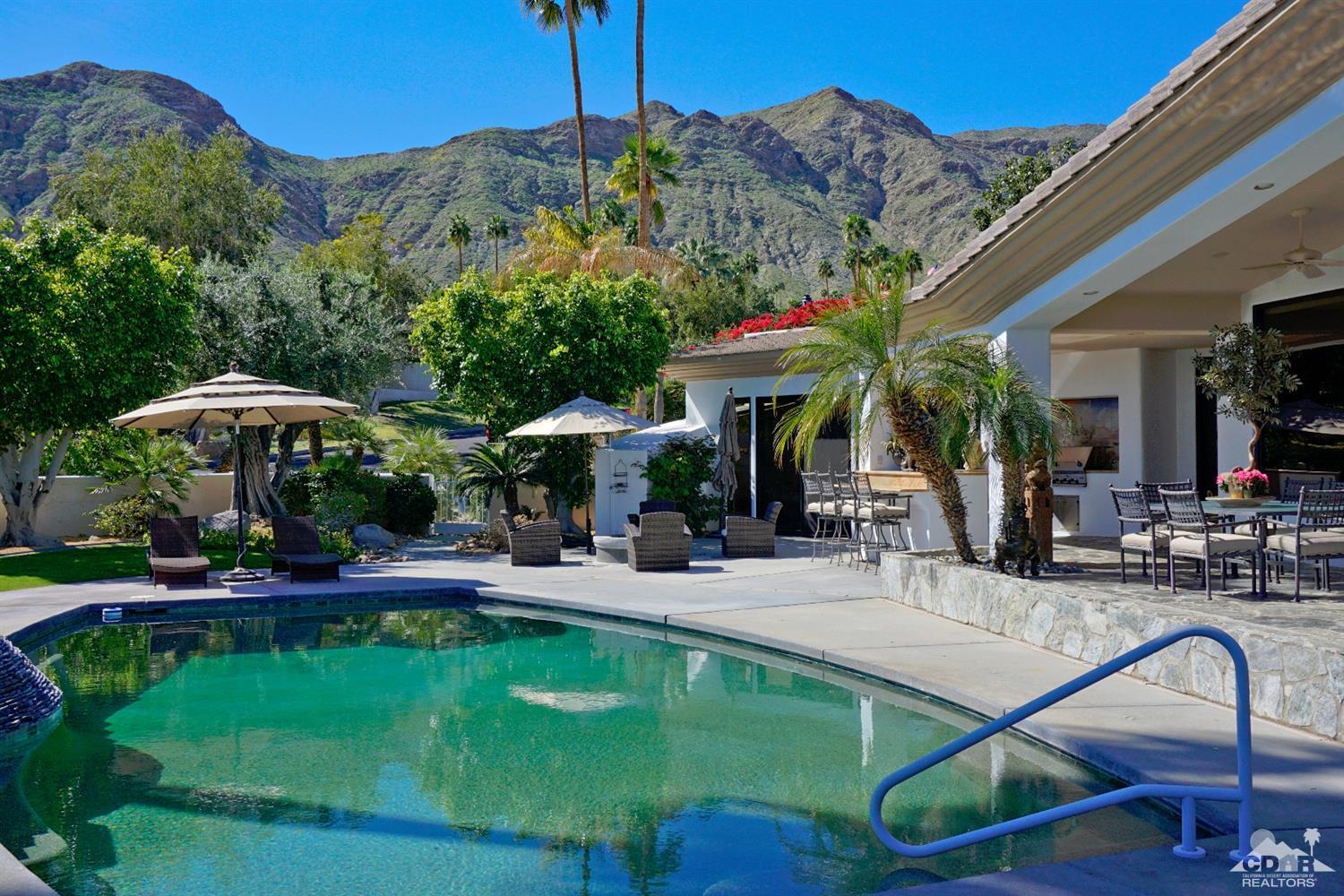 40815 Tonopah Road Rancho Mirage, CA 92270 - Photo 37 of 44 a view of a swimming pool with a table and chairs under an umbrella