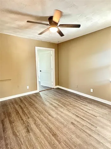 an empty room with wooden floor and a ceiling fan
