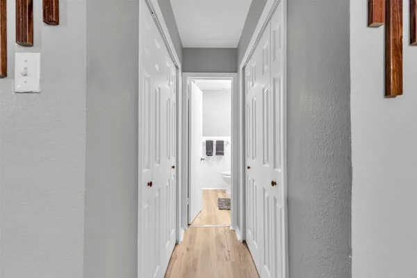 a view of a hallway with wooden floor and a bathroom