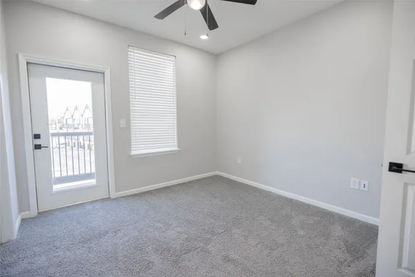 an empty room with chandelier fan and windows