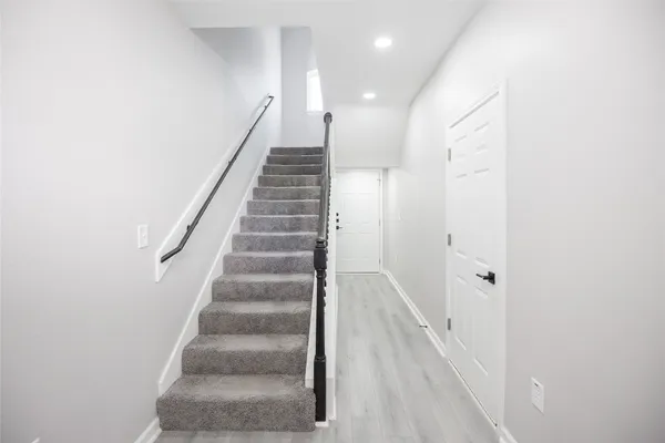 a view of staircase with white walls and white door