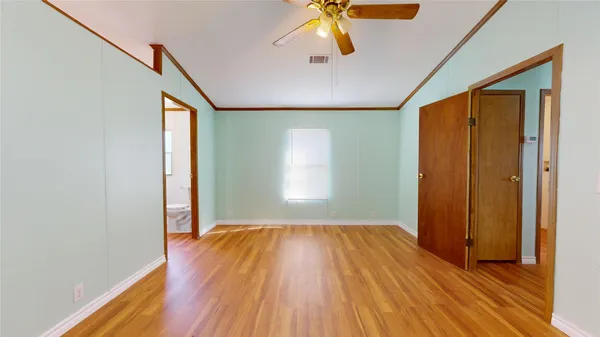 a view of empty room with wooden floor and fan