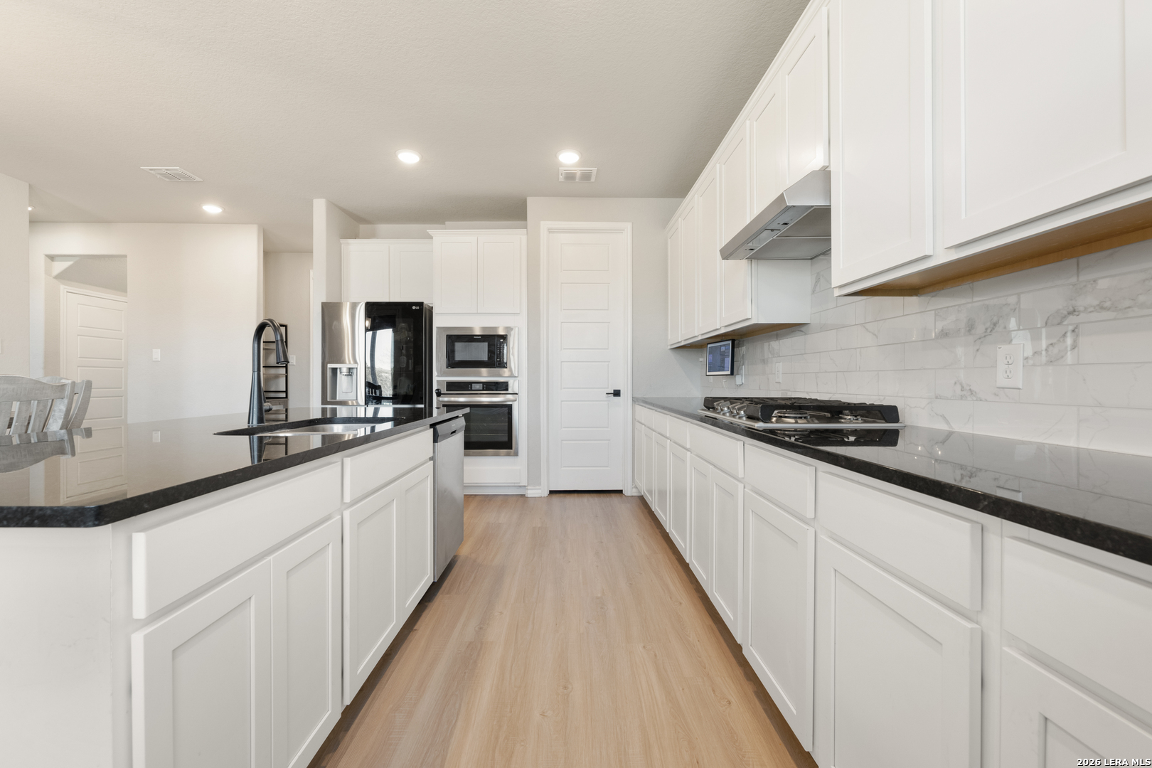 229 Jereth Crossing Castroville, TX 78009 - Photo 17 of 41 a large kitchen with stainless steel appliances kitchen island granite countertop a sink and cabinets