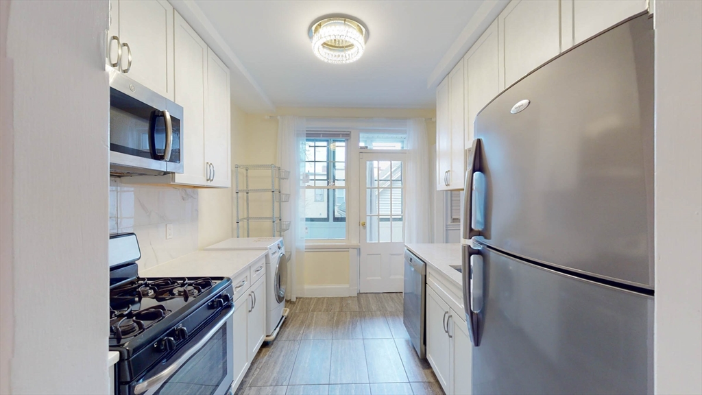 311 Tappan Street, Unit 3 Brookline, MA 02445 - Photo 13 of 35 a kitchen with stainless steel appliances a refrigerator a stove and white cabinets