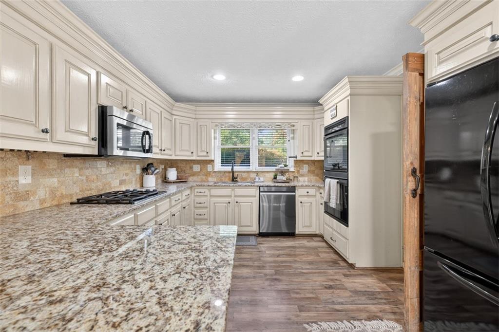 2380 Camp Mitchell Road Grayson, GA 30017 - Photo 19 of 56 a kitchen with stainless steel appliances granite countertop a refrigerator a stove a sink and white cabinets with wooden floor