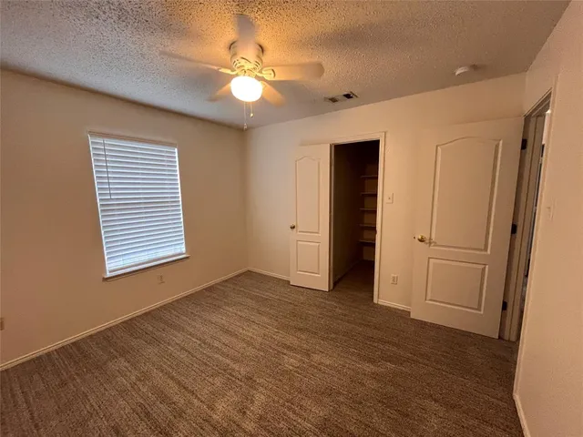 an empty room with chandelier fan and windows