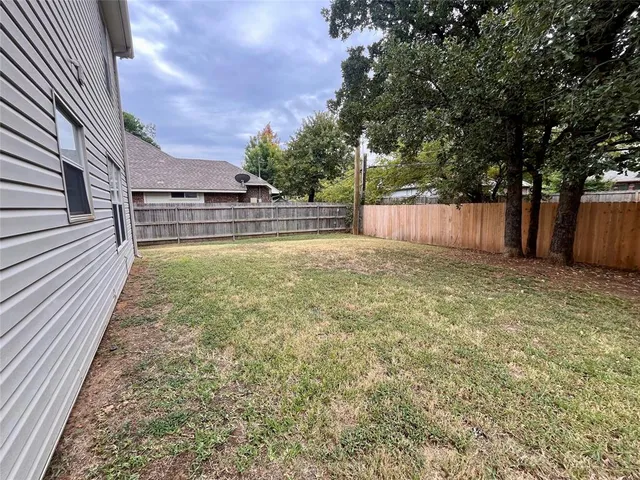 a view of a backyard with wooden fence and a large tree