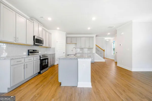 a large kitchen with cabinets wooden floor and stainless steel appliances