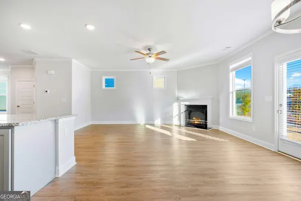an empty room with windows fireplace and a kitchen view