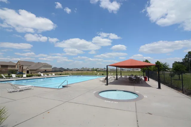 a view of a swimming pool with a table and chairs under an umbrella