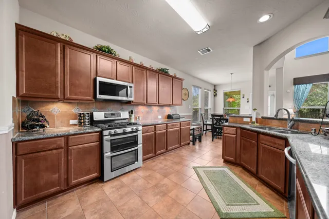 a kitchen with stainless steel appliances granite countertop wooden cabinets a stove top oven a sink and dishwasher