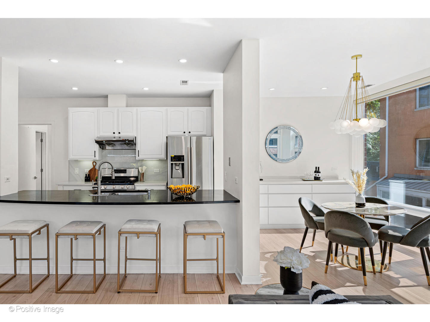 1151 West Washington Boulevard, Unit 136 Chicago, IL 60607 - Photo 5 of 19 a kitchen with stainless steel appliances kitchen island granite countertop a table chairs in it and white cabinets