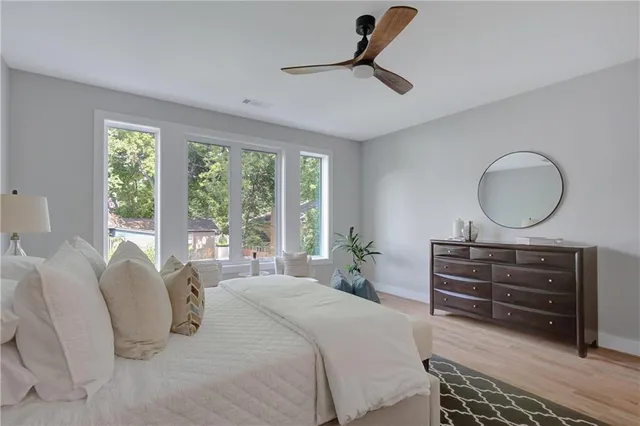 a bedroom with a bed a dresser and large window