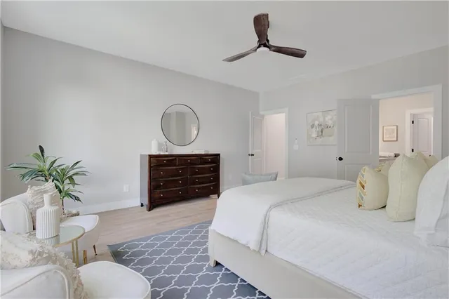 a bedroom with a bed and dresser with wooden floor