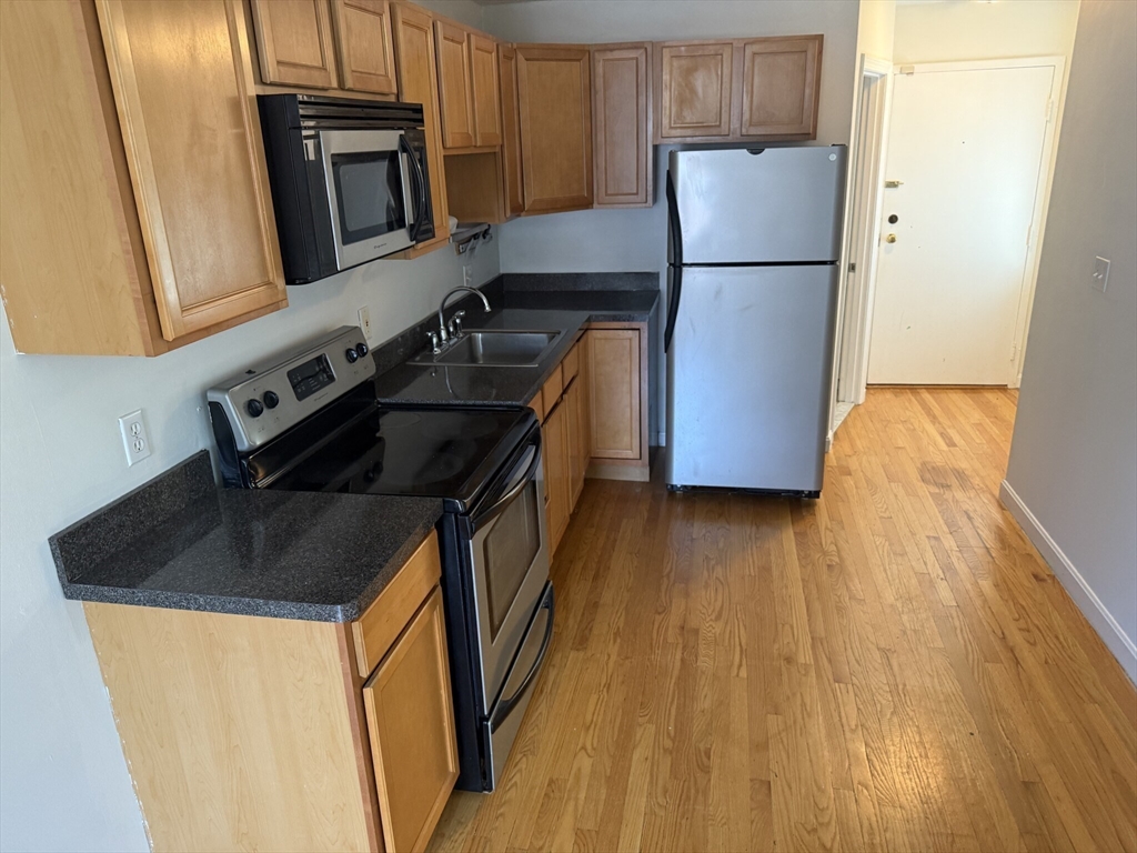 160 Cottage Street, Unit 2 Boston, MA 02128 - Photo 3 of 11 a kitchen with stainless steel appliances a refrigerator a stove a microwave and cabinets