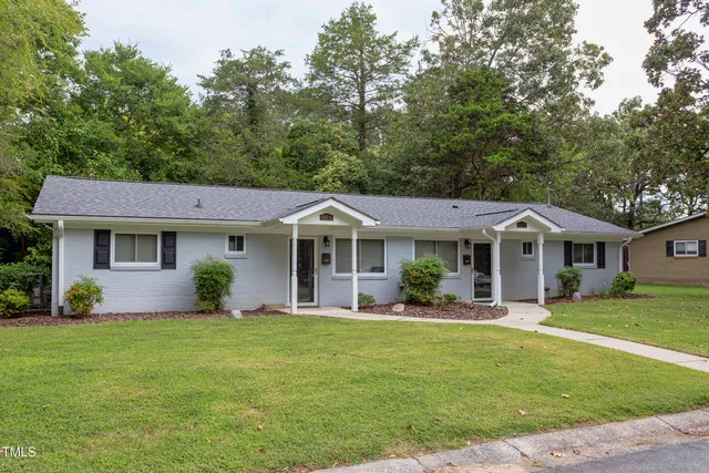 a front view of a house with garden and trees