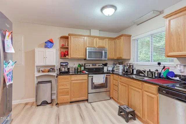 a kitchen with stainless steel appliances granite countertop a stove top oven a sink dishwasher and a refrigerator with wooden floor