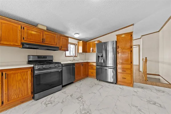 a kitchen with stainless steel appliances granite countertop a refrigerator stove top oven a sink and dishwasher
