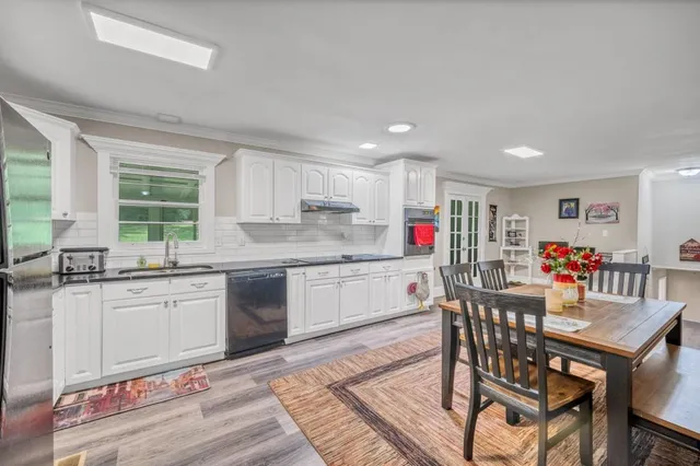 a kitchen with granite countertop kitchen island stainless steel appliances a stove a sink a dining table and chairs