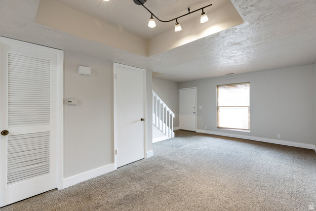 88 West 50 South, Unit J10 Centerville, UT 84014 - Photo 3 of 19 Spacious room featuring neutral carpeting, light gray walls, a window with blinds, white trim, and a contemporary track lighting fixture