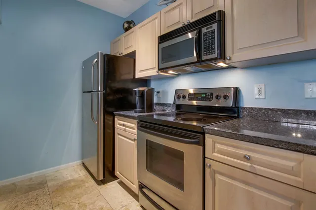 a kitchen with stainless steel appliances granite countertop white cabinets and a stove top oven