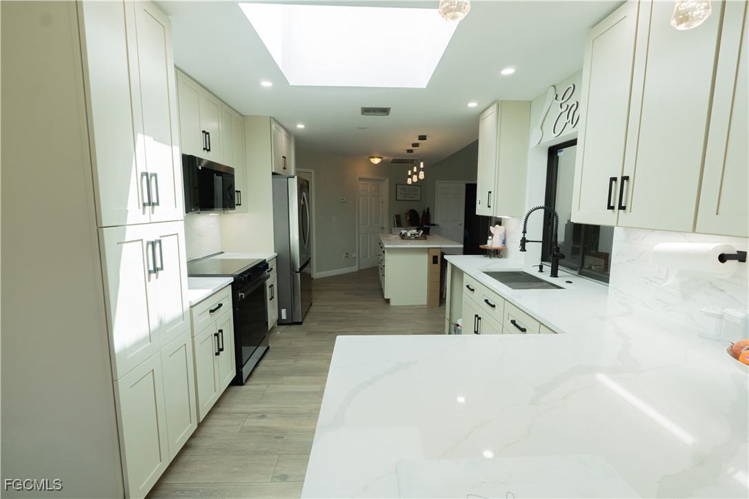 14557 Eagle Ridge Drive Fort Myers, FL 33912 - Photo 6 of 20 a large white kitchen with stainless steel appliances a large counter top a stove and a refrigerator