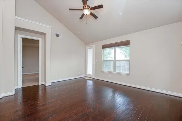 an empty room with wooden floor fan and windows