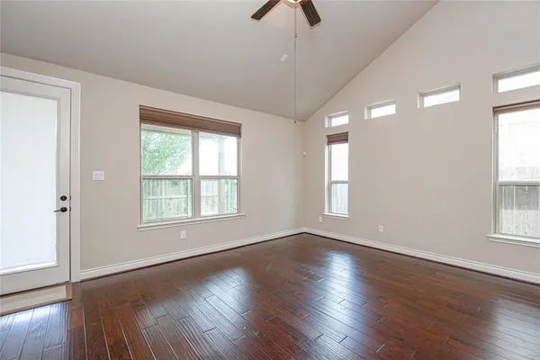 an empty room with wooden floor and windows