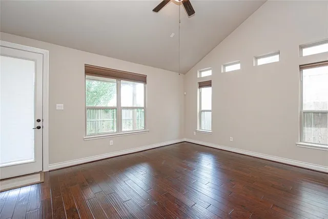 an empty room with wooden floor and windows