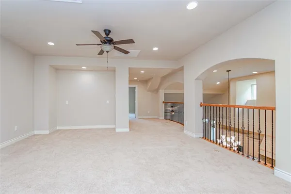 an empty room with chandelier fan and windows