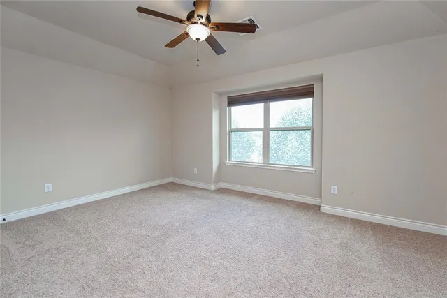 an empty room with a window and a fan