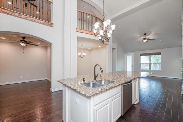a kitchen with a sink chandelier and wooden floor