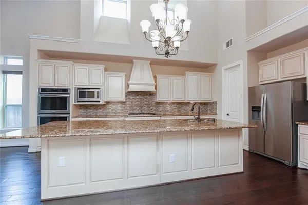 a kitchen with stainless steel appliances granite countertop a refrigerator a sink dishwasher and white cabinets with wooden floor