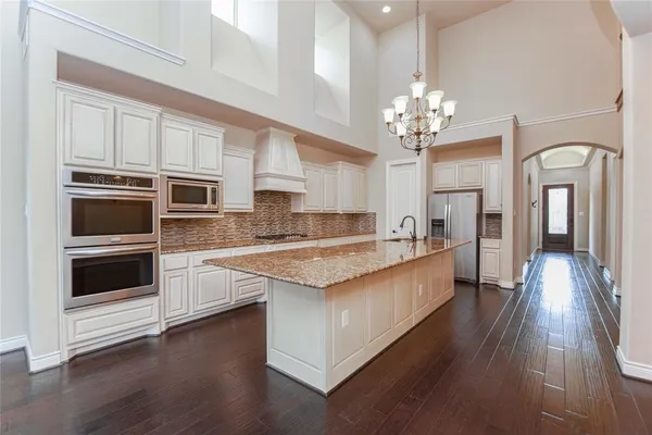 a large kitchen with stainless steel appliances granite countertop a lot of counter space and wooden floor