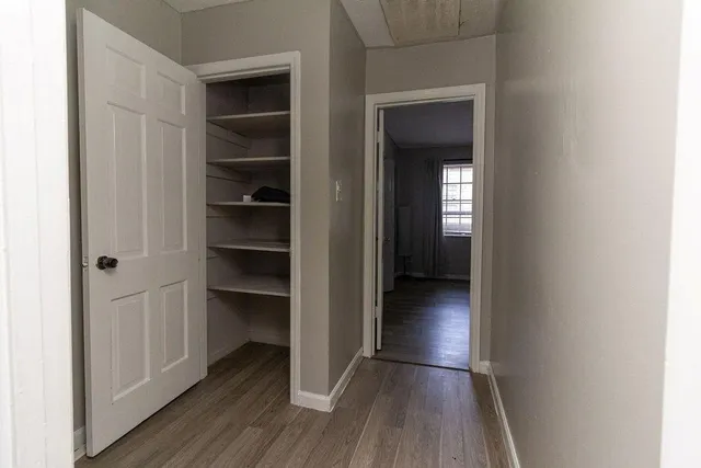 a view of a hallway with wooden floor and closet