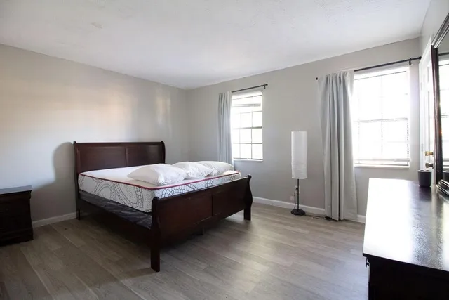 a bed sitting in a spacious bedroom next to a window