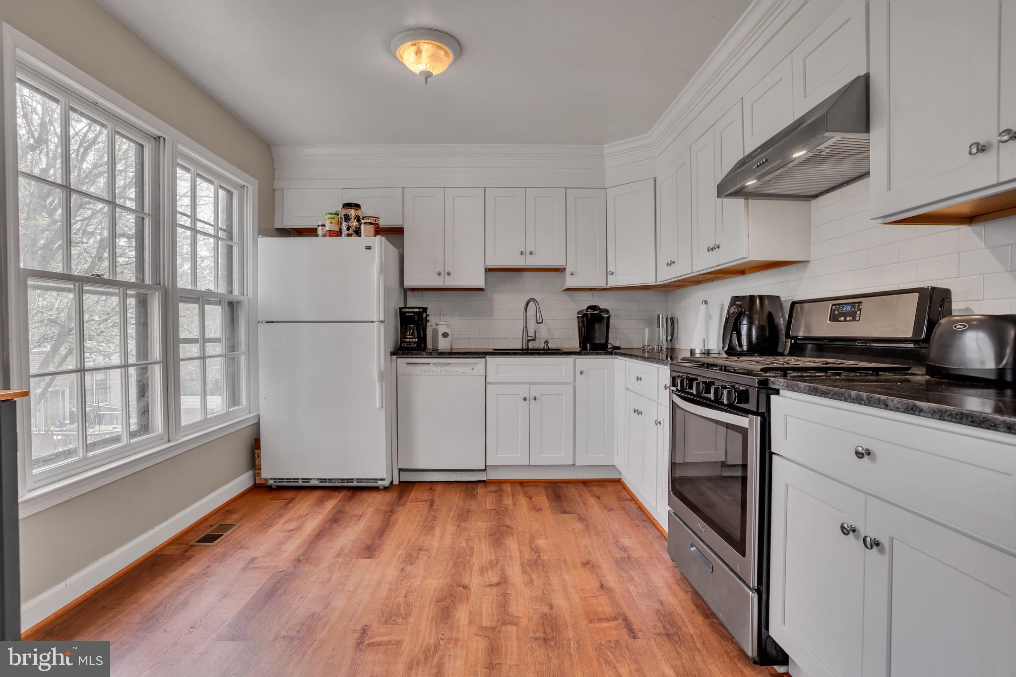 4926 Carriagepark Road Fairfax, VA 22032 - Photo 10 of 34 a kitchen with wooden floors and white appliances