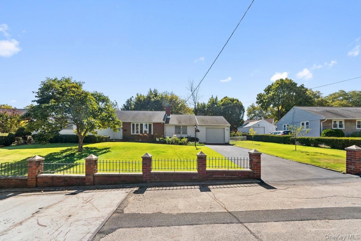 Ranch-style house featuring driveway, a fenced front yard, a garage, and a chimney