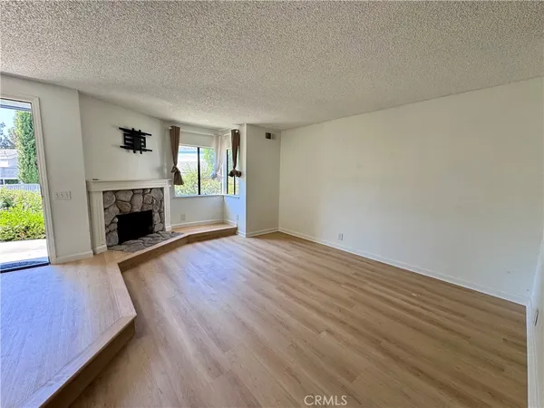 an empty room with wooden floor fireplace and windows