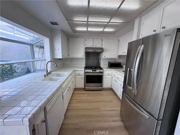 a kitchen with stainless steel appliances granite countertop a refrigerator a sink a stove and dishwasher
