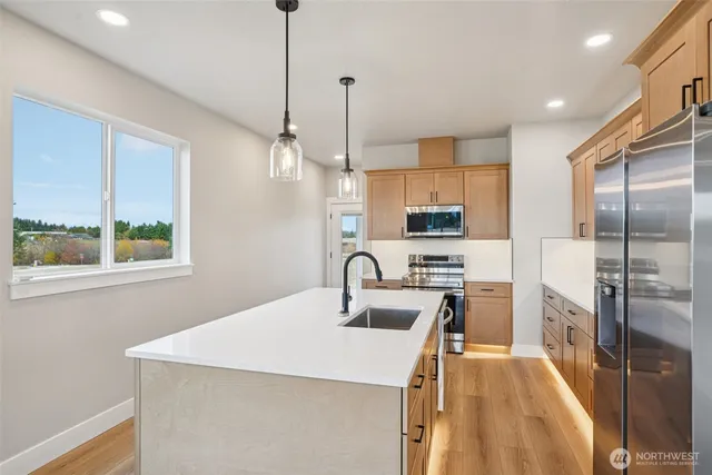 a kitchen with stainless steel appliances a sink a counter top space cabinets and a window