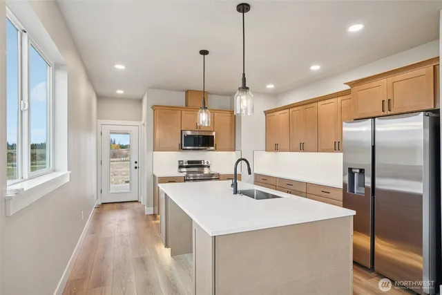 a kitchen with stainless steel appliances a sink a stove a refrigerator and cabinets