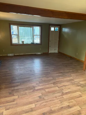 a view of an empty room with window and wooden floor