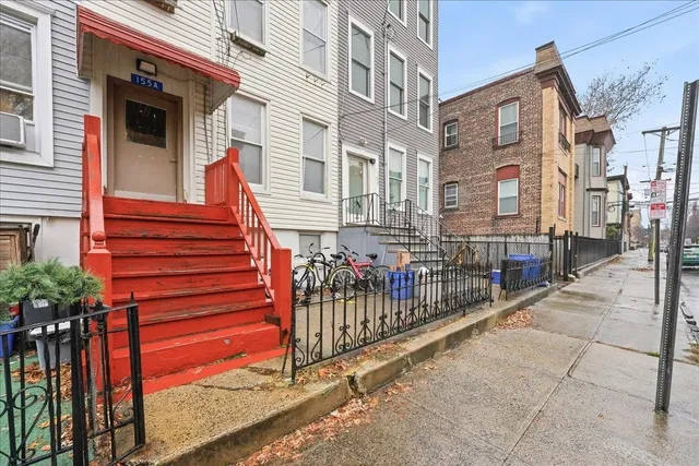 a view of a brick house with iron fence